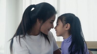 Genç Asyalı anne ve kız birbirlerine şefkatle sarılıp burunlarına dokunurlar. İlişki ve bağlılık için mutlu olan anne ve kız, duygu ve duygu, ebeveyn ve çocuk, aile kavramı..