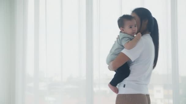 小さな赤ちゃんの女の子を保持し 家のベッドルームで一緒に歩く若いアジアの母親 お母さんは娘とケアを運ぶ 親子の関係 幼児と親 家族の概念 — ストック動画