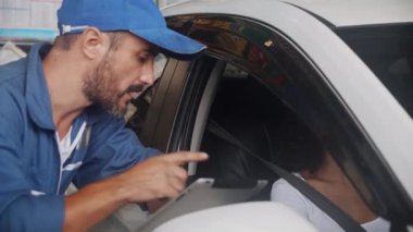 Müşteri genç kadın tamirciyle motor ve araba sorunları hakkında konuşuyor ve garajda anahtar araba veriyor, teknisyen aracı inceliyor ve müşterinin, iki kişinin, otomobil servisinin,.