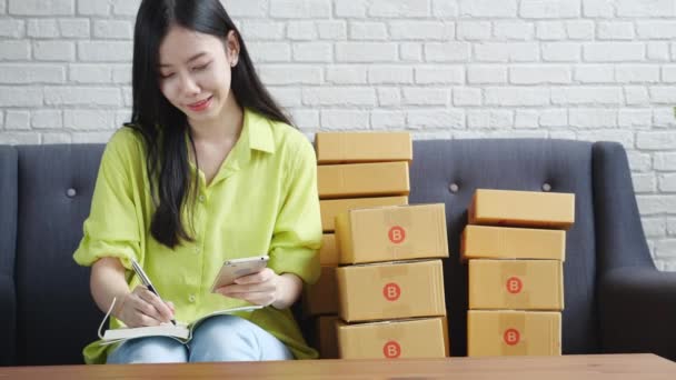 Mujer Asiática Joven Empresario Buscando Teléfono Escritura Orden Del Cliente — Vídeos de Stock