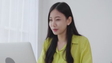 Genç Asyalı iş kadını internetteki video konferansı için sosyal mesafeli bilgisayar kullanıyor, iş kadını video çağrısı ile çalışıyor, yeni normal, iletişim ve ev kavramından çalışma.