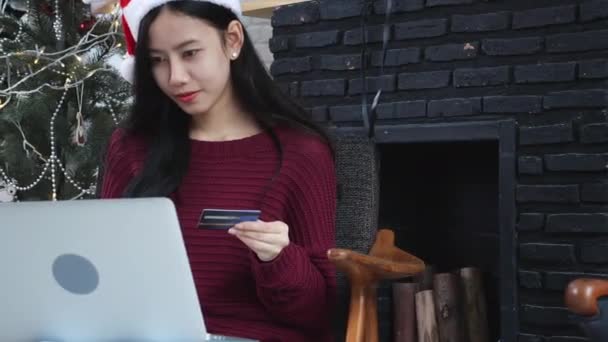 若いアジアの女性のオンラインショッピングクリスマスにクレジットカードでラップトップコンピュータ 女性の購入と支払いデビットカード クリスマス休暇中のクリスマス 幸せな新年 インターネットへの購入と顧客 — ストック動画