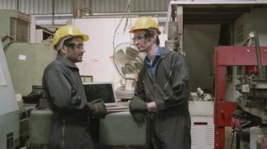 Takım çalışması mühendisi fabrika endüstrisinde çalışan arkadaşlarla konuşuyor, ustabaşı çalışana danışıyor, iki kişi iş ile tartışıyor ve plan yapıyor, bakım işçisi ve makine, endüstri konsepti.