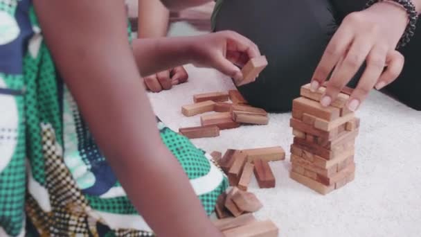 自宅のリビングルームで床におもちゃのブロックを再生若いアフリカの母親と娘 お母さんと小さな子供の活動の創造性とレジャーのためのゲームと開発 家族や教育の概念 — ストック動画