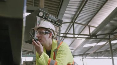 Üniformalı iki genç adam makineyi kontrol ediyor ve endüstriyel fabrikadan telsiz telefonuyla arıyor. Mühendis ve işçi kontrolü ve teknik problemleri olan denetleme makineleri..