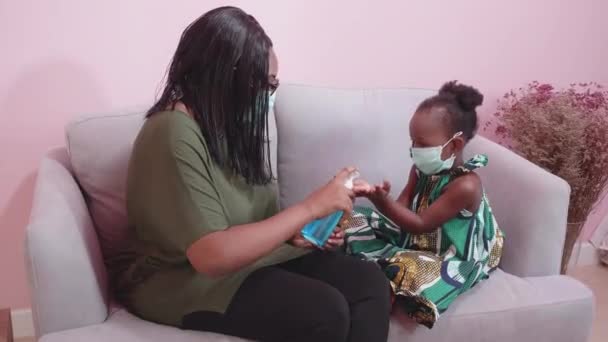 Африканская Мать Заботиться Дочь Носить Маску Лица Помощью Дезинфицирующего Средства — стоковое видео