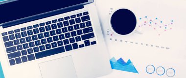 Dizüstü bilgisayar ve belgeler istatistiksel finans raporlarını masa başında grafik ve grafik ve kahve, finans ve yatırım, dijital pazarlama ve gelir, iş ve iletişim kavramının büyümesi.