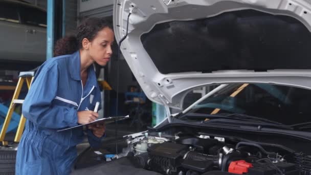 Mujer Mecánica Sujetando Portapapeles Mientras Examina Motor Del Coche Garaje — Vídeos de Stock