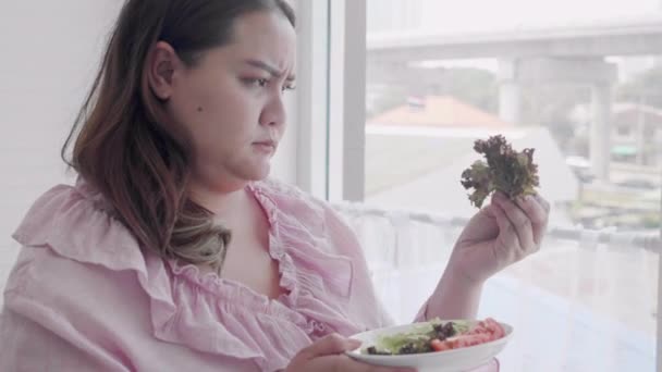 若いアジアの女性の脂肪は野菜のサラダを嫌い 女性は野菜を嫌いますが ダイエット減量 健康食品 女性の表情と感情 プラスサイズ 栄養と健康のためのデトックスのために食べる — ストック動画