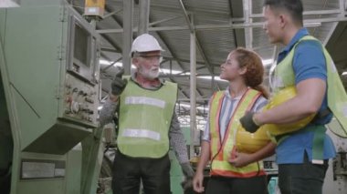 Bir grup mühendis endüstriyel fabrikada makine kontrolü kullanarak çalışıyor, ustabaşı stajyeri tartışıyor ve öğretiyor, insan çeşitliliği, kapalı alan, endüstri konsepti.