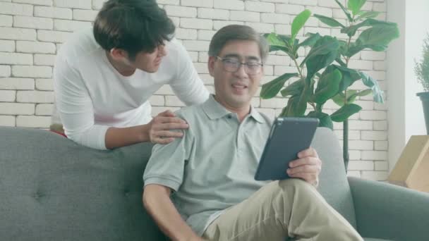 父と息子と幸せな家族がソファに座って 家でタブレットコンピュータに興味を持って話し合い 高齢者や若者がタブレットを見て話し合い コミュニケーションの概念 — ストック動画
