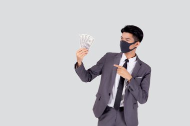 Yüz maskeli genç Asyalı işadamı para dolarını beyaz arka planda, salgın hastalıkta ve ekonomik krizde, tıbbi maske takan ve hastalık sırasında yatırım yapan işadamında izole etti..