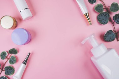 Pembe arka planda izole edilmiş krem ya da losyonlu makyaj şişesi ve yaprak, reklam, cilt bakımı ya da kozmetoloji, üst görünüm, düz döşeme, cilt bakımı ve ürün ile tedavi paketi.