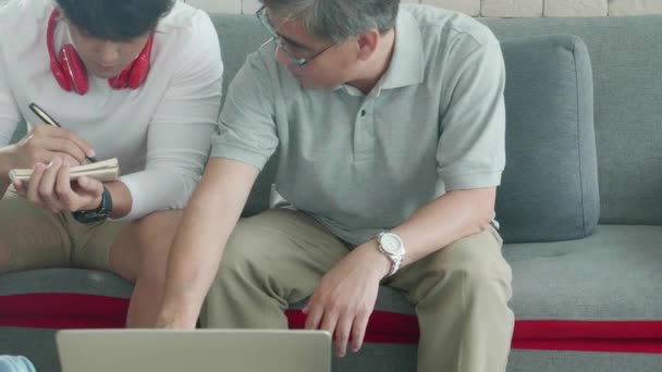 Rodzina Synem Siedzi Kanapie Patrząc Laptopa Pisanie Listy Kontrolnej Finansowania — Wideo stockowe