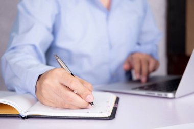 Dizüstü bilgisayarda webinar seyreden ve öğrenme, e-öğrenme, video konferansı ve eğitim, seminer kursu, bilgi ve dijital çalışma için not defterine yazan adamın eli.