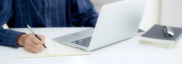 İş adamının eli, evdeki dizüstü bilgisayarı kullanırken notta yazdığı gibi, erkek iş başarısı, yazar ve blog, masa, çalışan ve iş için çalışan işadamı,.