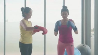 Genç Asyalı kadın ve spor giyim koçu eldiven eğitimi egzersizi giyiyorlar spor salonunda boks, kadın ve partner spor salonunda boks sporu, iki kişi, kapalı alanda..