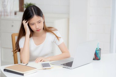 Genç Asyalı kadın başağrısı dizüstü bilgisayarda çalışırken son teslim tarihi evdeyken, iş kadını yorgun ve bitkin, stresli ve endişeli, hayal kırıklığına uğramış ve başarısız.