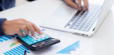 Muhasebecilik için hesap makinesi kullanan genç Asyalı iş adamının eli, finans ve rapor grafiği, istatistik, yatırım ve gelir kârı, grafikle analiz eden iş adamı.