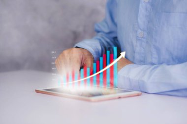 İşadamı tablet bilgisayarına yatırım ve finans grafiği, hisse senedi ve kar büyümesi, dijital pazarlama, finansal ve hedef planlama, iş ve iletişim kavramları ile dokundu.