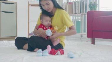 Mutlu bir aile, anne kucaklıyor ve evde çorap bebek giyiyor, anne ve kızını kucaklıyor ve ona bakıyor, güzel, kapalı, yaşam tarzları olan kadın ve bebek.