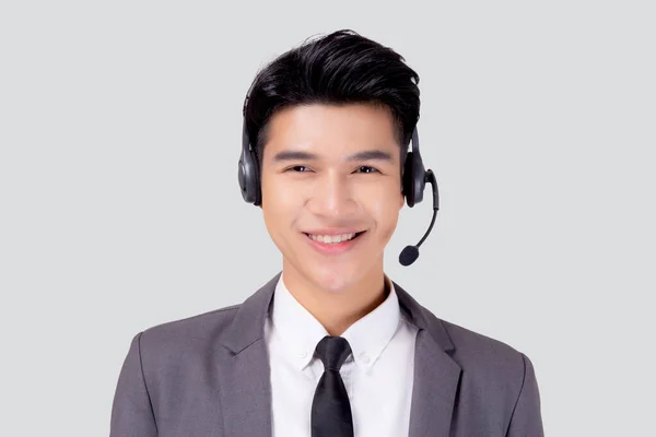Beyaz arka planda izole edilmiş kulaklık takan Asyalı genç bir iş adamı portresi, destek ve hizmet veren bir ajan, iş adamı internetteki telefon ya da yardım hattı olan bir müşteri asistanı.