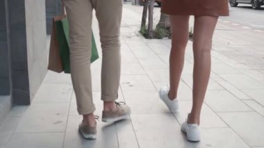 İki insanın birbirine yakın bacakları sokakta yürüyen ve alışveriş torbası tutan genç bir adam ve bir kadının arkadaşları birlikte alışveriş koliktir, çiftin ilişkisi tatmin edici tüketimciliktir..