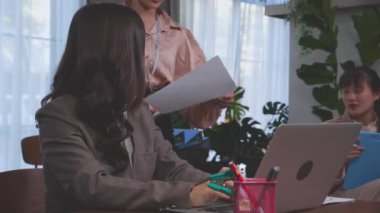 Genç çalışan raporları ofisteki genel müdürle muhasebe, sekreterin patrona ya da yöneticiye evrak işi vermesi, müdür yardımcılığının birlikte durması ve konuşması, iş konsepti..