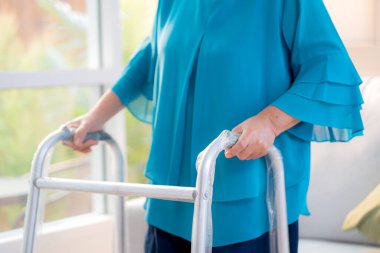 Yakın mesafede üst düzey Asyalı kadın Walker 'ı fiziksel terapi için kullanıyor evde yürürken, rehabilitasyonda, emeklilik sırasında yaşam tarzında, yaşlı kadın Walker' la destek için yürüyor..