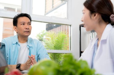 Klinikteki Asyalı beslenme uzmanı danışman hasta, yemek planı tartışması, sağlık hizmeti tavsiyesi, kilo kaybı desteği, doktorun konuşması ve hastaya beslenme danışmanlığı, sağlık bakımı.