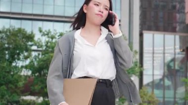 Genç Asyalı iş kadını stresli akıllı telefonla konuşurken yürüyor, iş kadını ciddi bir iş yöneticilik sorunu, kadın telefonda sorun tartışması yaparken endişeli.