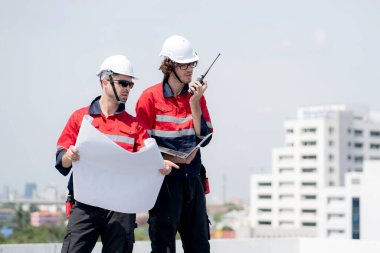 Güneş enerjisi sistemini kontrol eden iki mühendis, telsiz, yenilenebilir enerji, endüstri ve güneş pili üzerine konuşurken, birlikte güneş paneli kurma planlarını inceliyor..