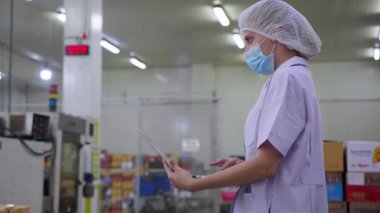 İşçi kadın müfettiş gıda işleme fabrikasında kalite kontrolde çalışıyor, üniformalı kadın ve maske, dizüstü bilgisayar kullanarak hijyen ve üretimi izliyor, kadın kalite ve tedarik zincirini inceliyor..