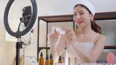 Genç Asyalı kadın kozmetik ürünlerini sosyal medya platformunda takipçiler, krem ya da losyonu canlı yayında inceleyen, etkileyen ve gözden geçiren kadınlar için heyecan verici bir şekilde sunup gözden geçiriyor..
