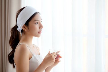 Saç bandı takmış, çay içen güzel, genç Asyalı bir kadın. Oturma odasından memnun, çay ya da içecek bir kadın. Sağlık ve rahatlama, yaşam tarzı ve sağlık için..