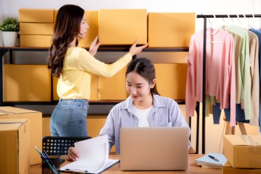 İki genç Asyalı iş kadını dizüstü bilgisayar ve belge, sevkiyat ve kargo, perakende satış ve mağaza, başlangıç veya küçük işletme, nakliye ve envanter siparişlerini kontrol ediyor.