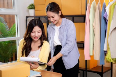 Çevrimiçi iş ve düzeni, girişimciyi ve küçük işletmeyi yönetirken ve planlarken, belgeyi kontrol ederken ve kontrol ederken, Asyalı iki kadın, çevrimiçi satıcı ile perakende satış, girişim işi.