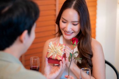 Romantik Asyalı erkek sevgilisine hediye paketi veriyor. Sevgililer günü için sürpriz ya da restoranda yıldönümü yemeği. Mutlu çift, aşkı hediyeyle, mutlulukla ve ilişkiyle kutluyor..