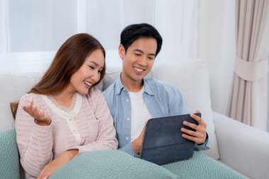 Mutlu Asyalı çiftler, evdeki oturma odasında birlikte otururken, kadın ve erkek evde sanal alemden, teknoloji bağlantısından ve sosyal medya etkileşiminden, ilişkiden ve bağlanmadan bahsediyorlar..