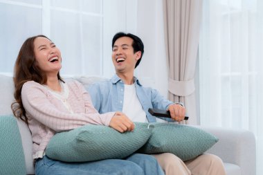 Mutlu Asyalı çift birlikte televizyon seyrediyor. Oturma odasındaki kanepede oturup uzaktan kumandayla film kanalını değiştiriyorlar. Bir çift medya eğlencesinin tadını çıkarıyor..