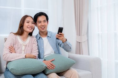 Mutlu Asyalı çift birlikte televizyon seyrediyor. Oturma odasındaki kanepede oturup uzaktan kumandayla film kanalını değiştiriyorlar. Bir çift medya eğlencesinin tadını çıkarıyor..