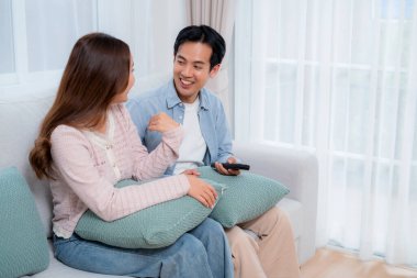 Mutlu Asyalı çift birlikte televizyon seyrediyor. Oturma odasındaki kanepede oturup uzaktan kumandayla film kanalını değiştiriyorlar. Bir çift medya eğlencesinin tadını çıkarıyor..