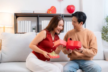 Romantik Asyalı çift, evde doğum günü ya da bayram kutlaması için kalp hediye kutusu veriyor ve alıyor. Sevgililer günü ya da tatilini aşkla kutluyor, romantik sevgililer günü festivali, heyecan hissediyorlar..