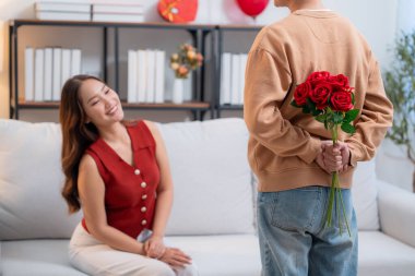 Sevgililer Günü 'nü kutlamak için gül buketi saklayan Asyalı romantik bir adam. Ya da evde sevgililer günü ya da yıldönümü kutlamalarıyla. Neşeli beklentilere aşık genç bir çift..