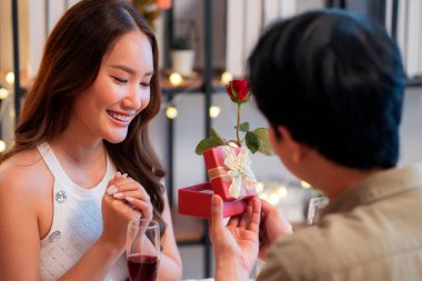 Romantik Asyalı erkek sevgilisine hediye paketi veriyor. Sevgililer günü için sürpriz ya da restoranda yıldönümü yemeği. Mutlu çift, aşkı hediyeyle, mutlulukla ve ilişkiyle kutluyor..
