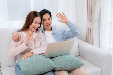 Mutlu Asyalı çiftler dizüstü bilgisayarda birlikte oturdukları evde, kadın ve erkek evde sanal ortamdan, teknoloji bağlantısından ve sosyal medya etkileşiminden, ilişkiden ve kaynaşmadan bahsediyorlar..