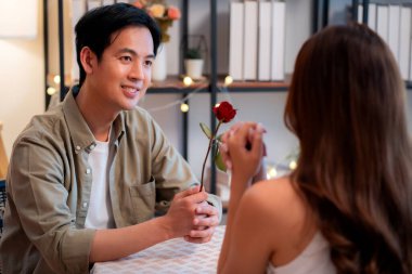 Romantik Asyalı bir adamın akşam yemeği sırasında kadına gül vermesi, Sevgililer Günü ya da yıldönümü kutlaması için sürpriz bir hediye, restoranda birbirine aşık çift, aşkı hisseden ve bağ kuran çift..