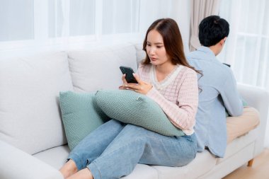 Mutsuz Asyalı çift ilişki sorunu yaşıyor, kadın üzgün görünüyor, erkek ise akıllı telefon, çatışma ve evdeki kanepe, sosyal medya bağımlılığı, stres ve gerilim için partnerini görmezden geliyor..