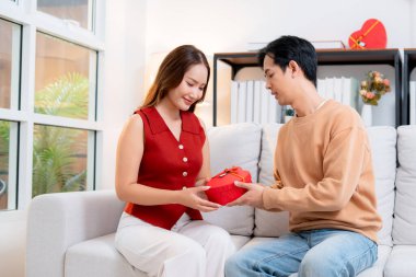 Mutlu Asyalı adam Sevgililer Günü 'nü ya da yıldönümünü evde kutlayan sevgilisine kalp hediye kutusu veriyor. Mutlu sürpriz hediyeye aşık genç bir çift, ilişki ve kaynaşma..