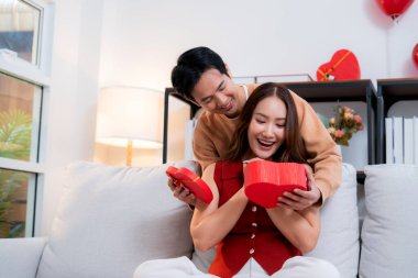 Mutlu Asyalı adam Sevgililer Günü 'nü ya da yıldönümünü evde kutlayan sevgilisine kalp hediye kutusu veriyor. Mutlu sürpriz hediyeye aşık genç bir çift, ilişki ve kaynaşma..